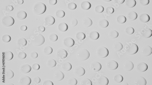 Many large shiny water droplets on glass on white studio background. Water splashes of rain. Aqua particle creative advertising concept.