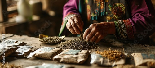 Seated female organizing dried seeds in envelopes, close up view.