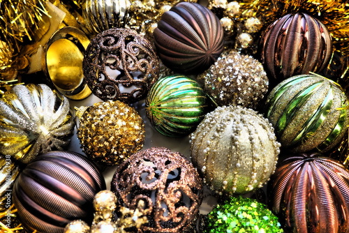 New Year's Christmas balls, tinsel and decorations close up. A lot of decoration of golden, brown, yellow, green. Striped Christmas balls. Festive beautiful colorful background. Home holidays design.