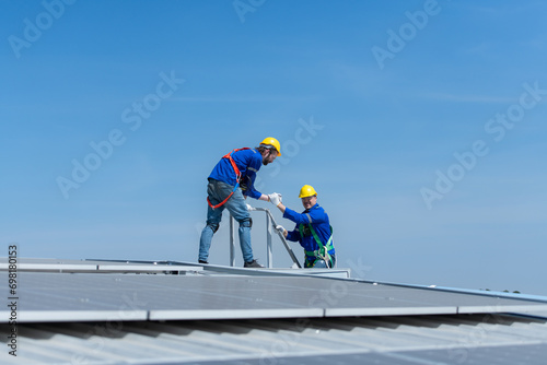 A young technician intern working on solar panels is fear of heights with senior engineers who are always helping out © Wosunan