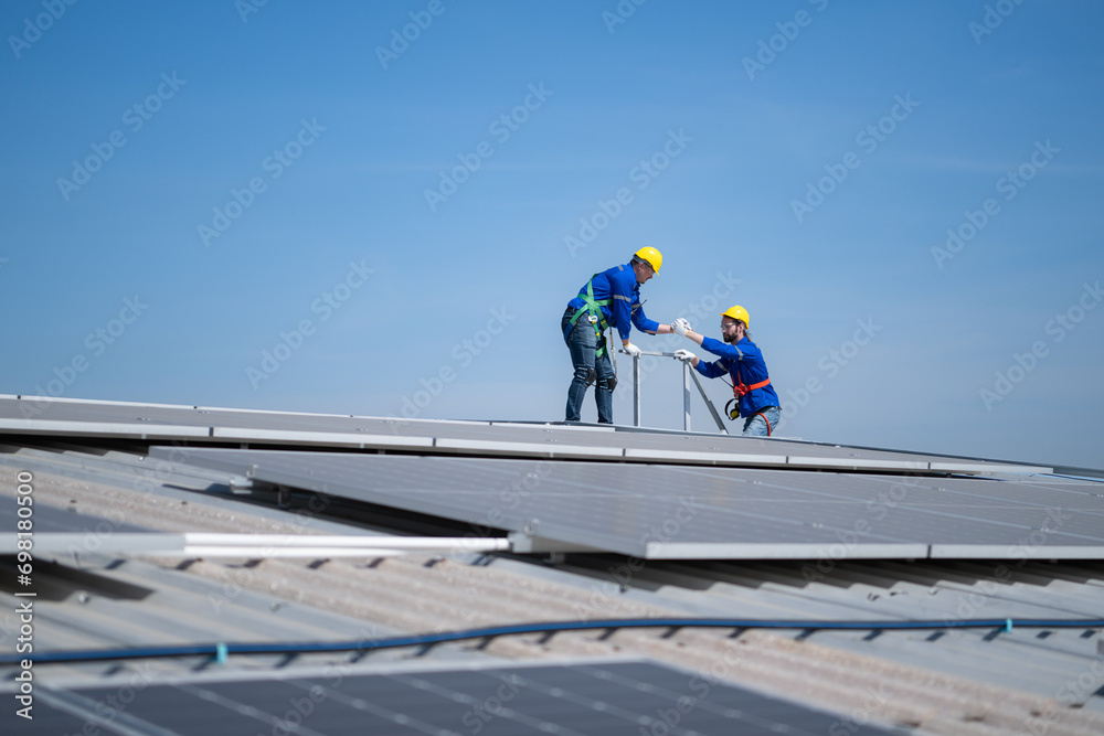 A young technician intern working on solar panels is fear of heights with senior engineers who are always helping out A young technician intern working on solar panels is fear of heights with senior engineers who are always helping out