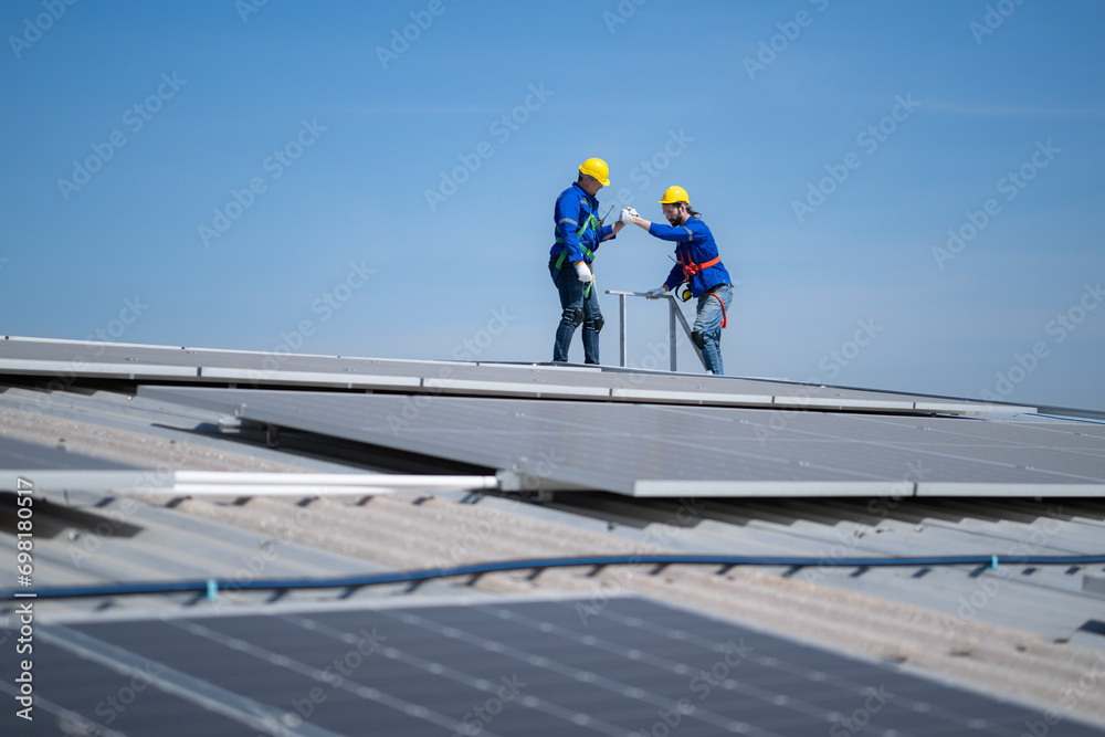 A young technician intern working on solar panels is fear of heights with senior engineers who are always helping out A young technician intern working on solar panels is fear of heights with senior engineers who are always helping out