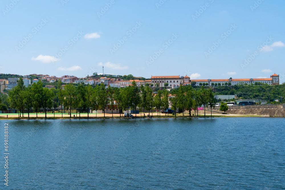 A view of the Mondego River and Coimbra City under a clear sky, with trees and buildings. Landscape background and wallpaper.