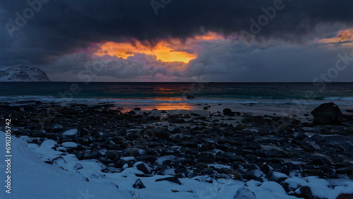  Lofoten winter landscape. Snow covered rocky shore in a colorful cloudy sunset. Lofoten, Northern Norway.