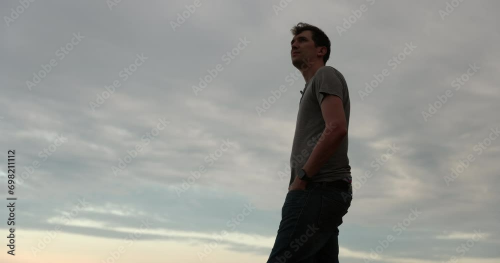 Man breathing deeply contemplating at sunset turns and walks away - side profile Man breathing deeply contemplating at sunset turns and walks away - side profile