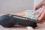 counting american dollars on pos machine on pink background