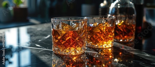 Three geometric whiskey glasses with transparent patterns stand on a reflective black glass.