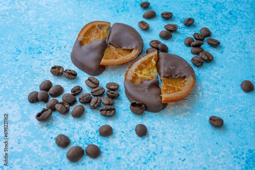 coffee beans and dried orange chocolates on blue background