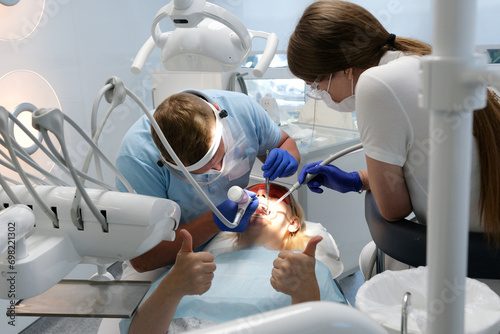 Professional male dentist examining and performing treatment to teenage girl . High quality photo