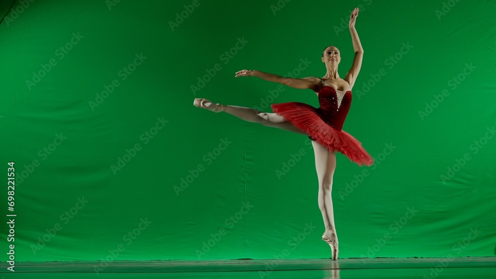 Woman on chroma key background of green screen. Beautiful ballerina in red tutu and pointe shoes dancing on toes choreography in studio.