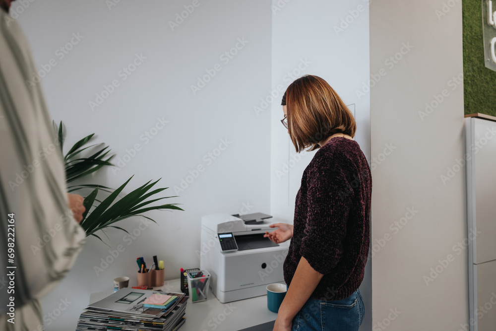 Young coworkers collaborating on a new project, analyzing data, and following trends for business growth. Business teammates printing documents at work.