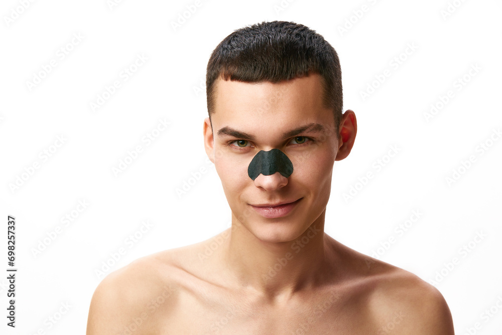 Handsome young man taking care after skin, applying mask for blackheads against white studio background. Concept of male beauty, skin care, spa, cosmetology, men's health Handsome young man taking care after skin, applying mask for blackheads against white studio background. Concept of male beauty, skin care, spa, cosmetology, men's health