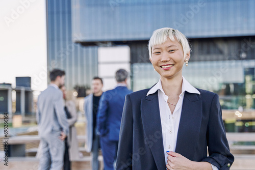 Wallpaper Mural Portrait of a young Asian businesswoman smiling while her team is talking in the background. Torontodigital.ca