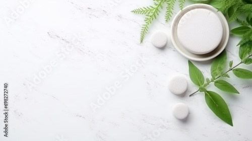  a white table topped with green leaves next to a bowl filled with white pills and a cup of pills on top of it.