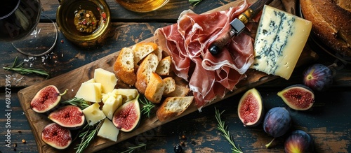 Prosciutto and cheese appetizers with figs on a wooden board, top view.