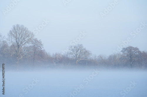Scenic view of a snowy landscape on a foggy winter day