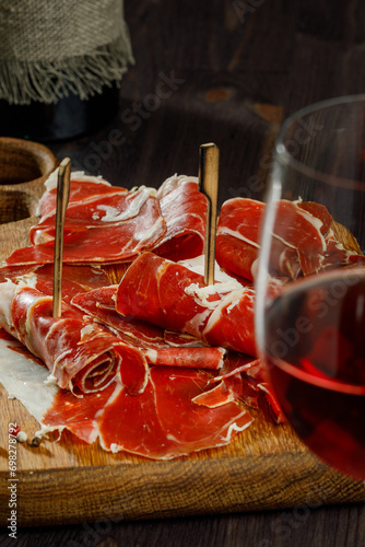 Slices of jamon serrano, jamon iberico, smoked sausage, ham or prosciutto crudo parma on wooden board with. Wooden background. Still life. Selected focus.