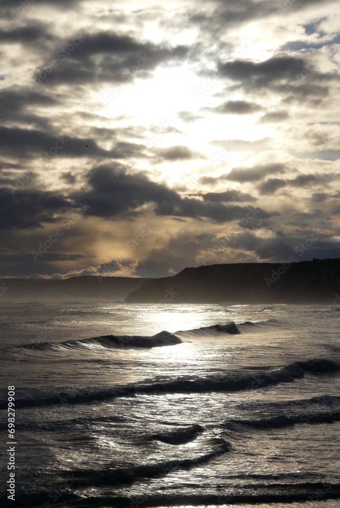 waves roll along the beach during the sun sets in the background