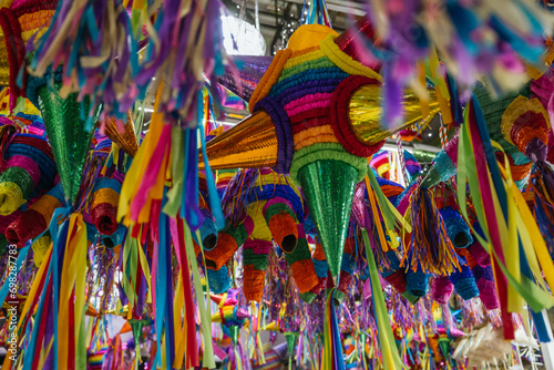 Colorful piñatas of different shapes and sizes hanging over the stalls of a traditional Mexican market.
