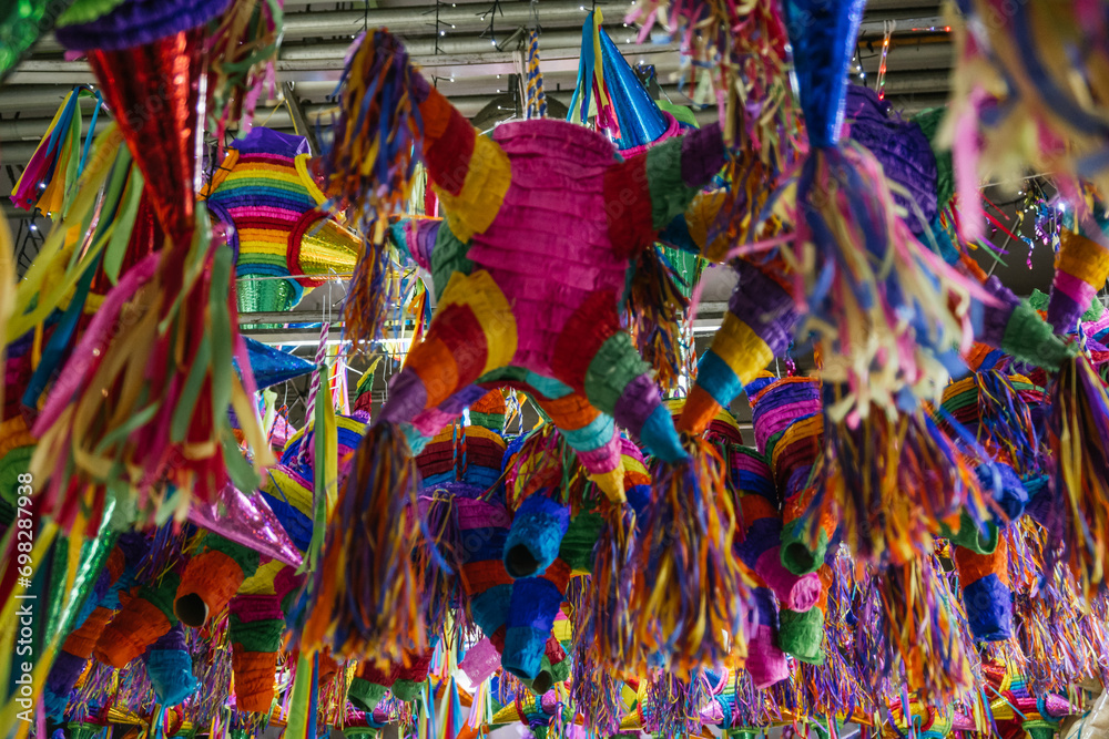 Fototapeta premium Colorful piñatas of different shapes and sizes hanging over the stalls of a traditional Mexican market.