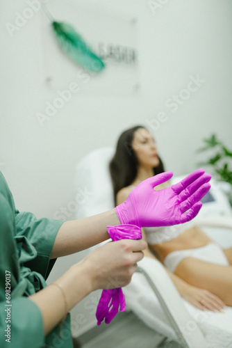 Beauty master makes laser hair removal of legs close-up in a beauty salon for a girl in glasses with beautiful pricked lips