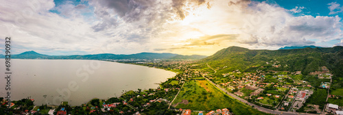 A panorama of mountains and lake with the sunset as background. Clouds and blue sky with trees and colors photo
