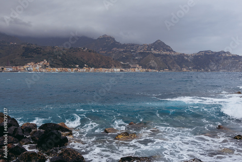 View from coast in Giardini Naxos in the Metropolitan City of Messina on the island of Sicily, Italy. Taormina city and Castelmola town on background photo