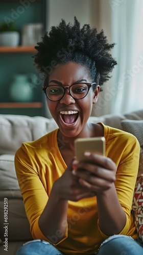 Joyful African American Woman Celebrating with Smartphone at Home