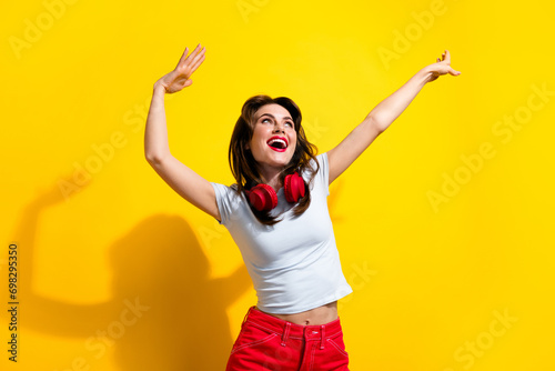 Photo of funky sweet woman dressed white t-shirt headphones having fun discotheque looking empty space isolated yellow color background photo
