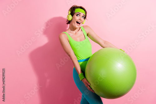 Photo portrait of lovely young lady listen music hold pilates ball dressed stylish green sport jumpsuit isolated on pink color background