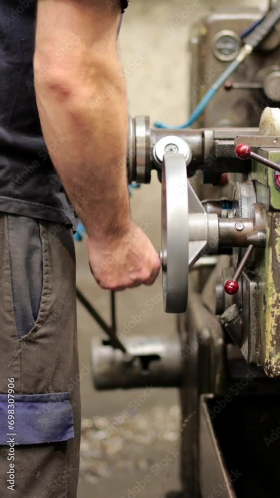 Close-up video of a man turning the crank of an industrial machinery in a cnc factory