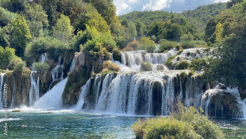 Fototapeta Naklejka Na Ścianę i Meble -  Scenic view of a waterfall surrounded by lush, green vegetation