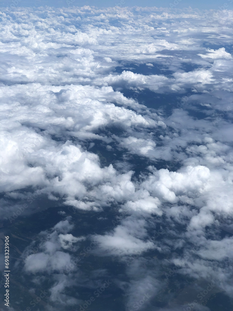 Aerial view of a cloudy sky seen through the window of an airplane Aerial view of a cloudy sky seen through the window of an airplane