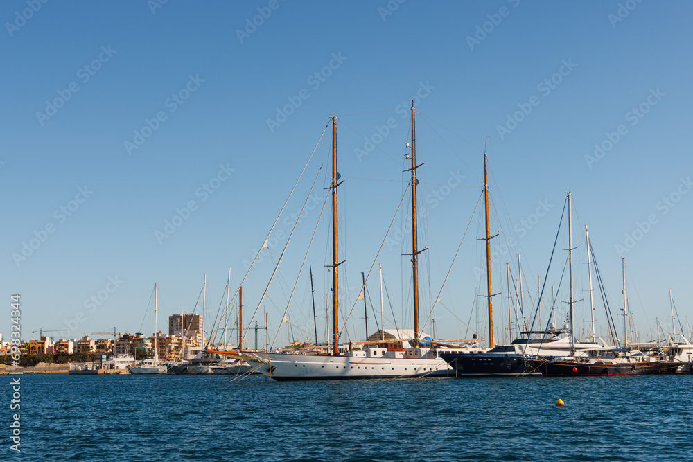 Classic wooden sailing yachts stand in the marina.