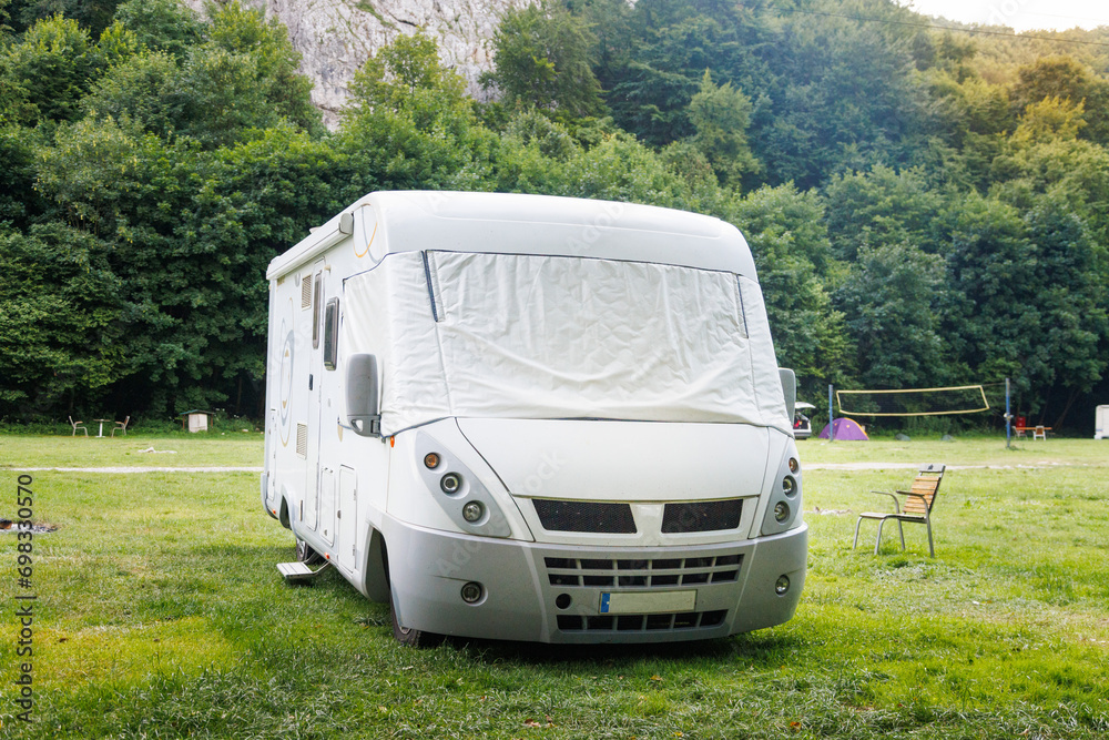 Motor home standing on a meadow near the forest and mountains.