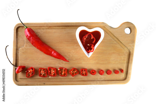 wooden board with red pepper cut into slices hot sauce with copy space white background