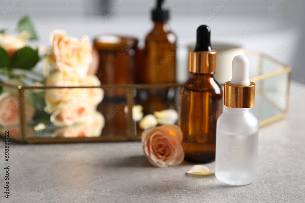 Bottles of cosmetic serum and beautiful flower on gray table, closeup Bottles of cosmetic serum and beautiful flower on gray table, closeup