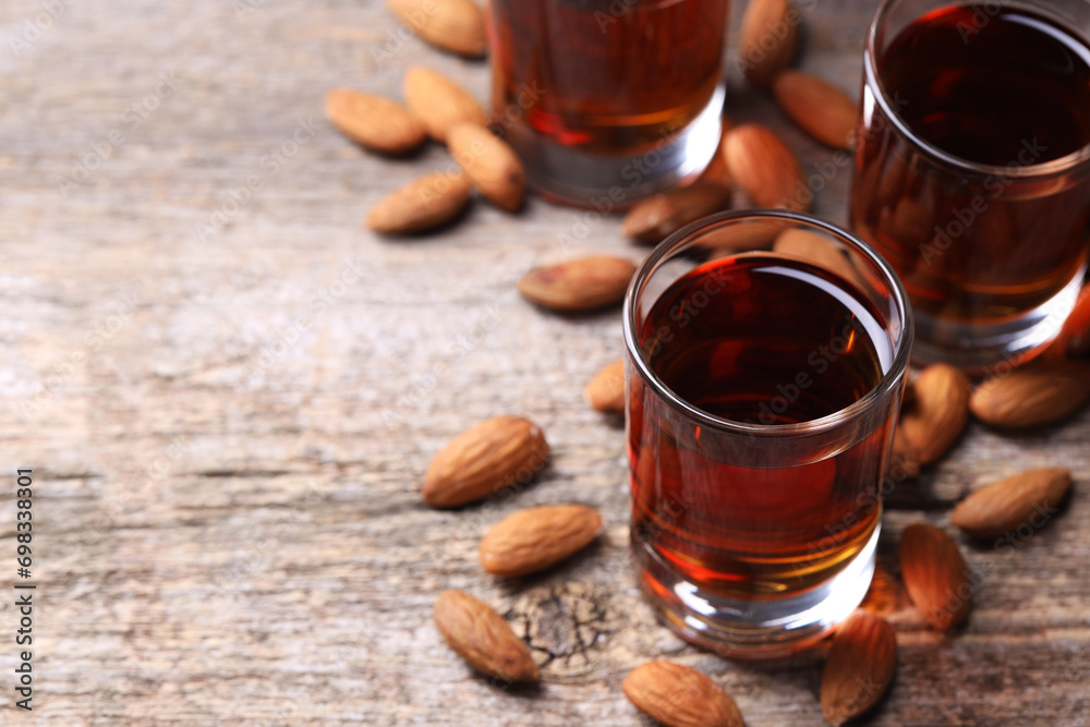 Shot glasses with tasty amaretto liqueur and almonds on wooden table, closeup. Space for text Shot glasses with tasty amaretto liqueur and almonds on wooden table, closeup. Space for text