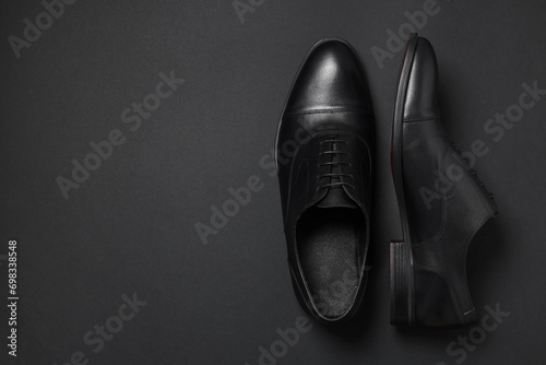 Pair of leather men shoes on black background, top view. Space for text