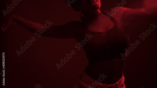 Black woman performing choreography under red lights