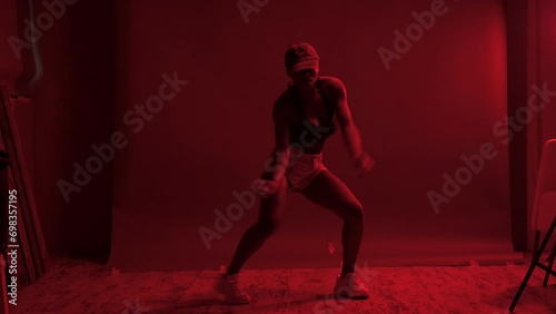 Black woman performing choreography under red lights