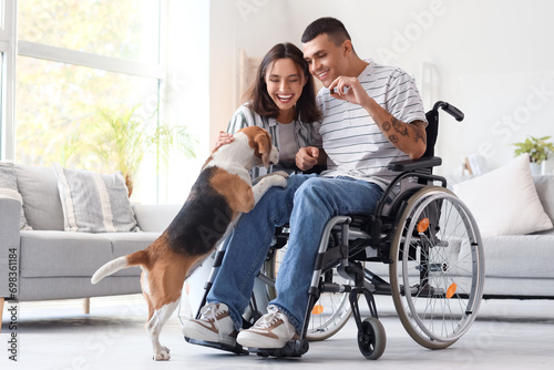 Young man in wheelchair and his wife with Beagle dog at home photo