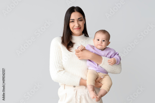 Happy mother with her little baby on light background