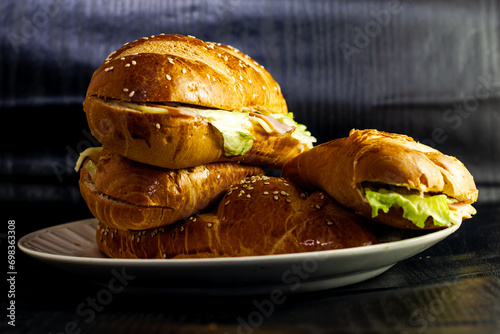 studio photography of sandwich on dark background with open bread with cheese ham lettuce and mayonnaise on a plate for breakfast