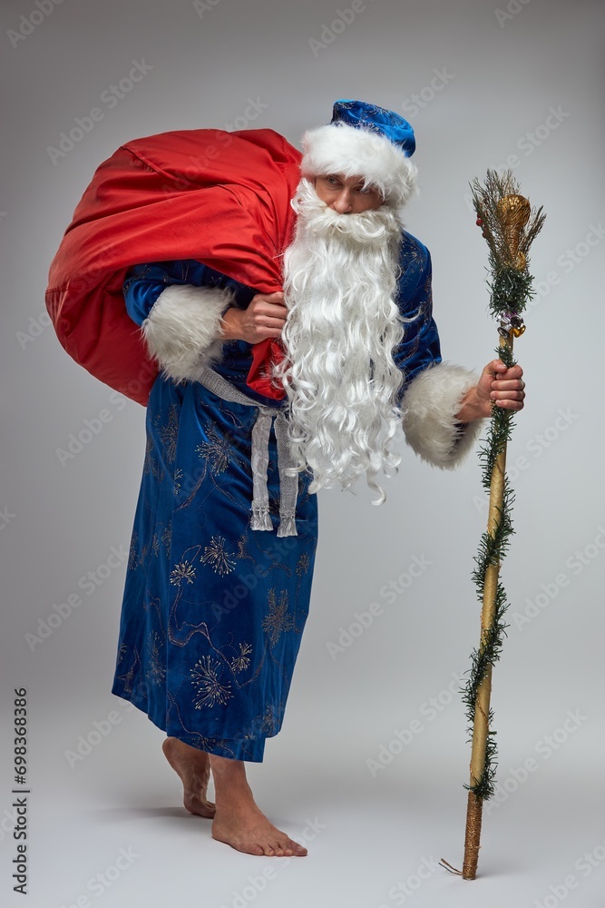 Barefoot Father Frost with staff carrying a bag of presents on his back