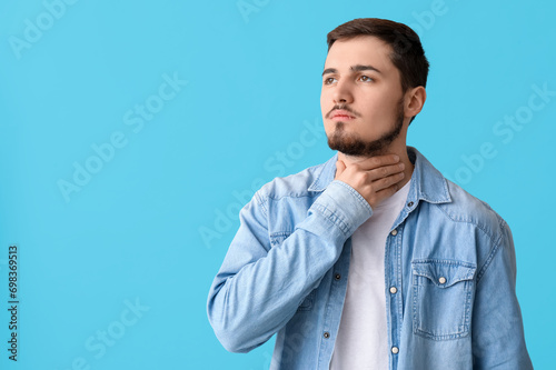 Young man with thyroid gland problem on blue background