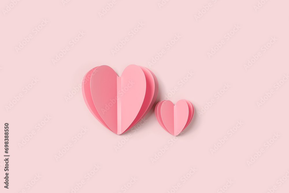 Two Pink paper hearts on pink colored background. Minimal style flat lay, pastel monochrome colors, valentine card or wedding invitation. Paper cut romantic concept, big ans small hearts