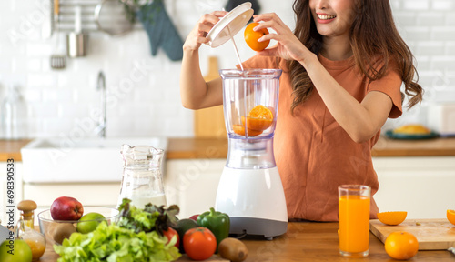 Portrait of beauty healthy asian woman making orange fruit smoothie with blender.girl preparing cooking detox cleanse with fresh orange juice in kitchen at home.health, vitamin c, diet, healthy drink