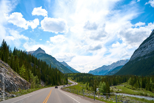 Beautiful view from a car on the Rocky Mountains in Banff National Park in Alberta. Panorama of a road in the mountains past a coniferous forest on a sunny day in summer.