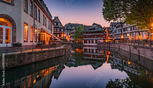 Ornate traditional half timbered houses with blooming flowers along the canals in the Petite France district of Strasbourg, Alsace, France at sunset © SvetlanaSF